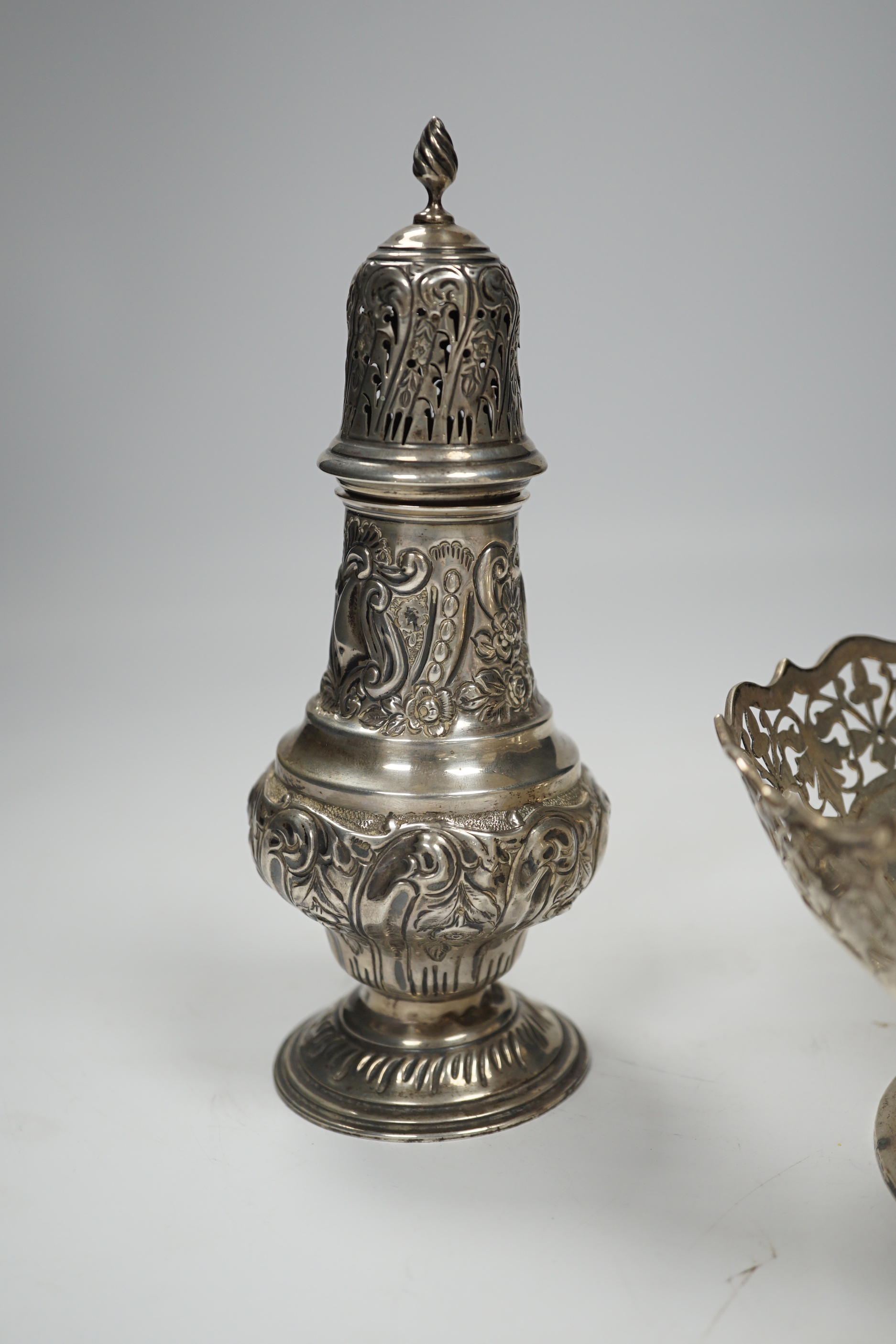 An Edwardian embossed silver sugar caster, Birmingham, 1904, 17.6cm and white metal cake basket stamped 'silver'.